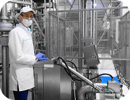 Food industry worker in protective clothing operating AI-powered manufacturing equipment