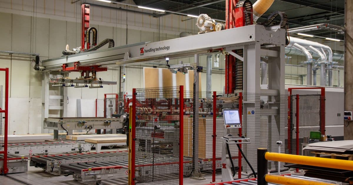 Automated robotic gantry handling system with control panel on a modern factory floor