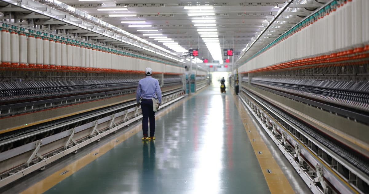 Worker walking through an automated spinning line in an Indian textile plant